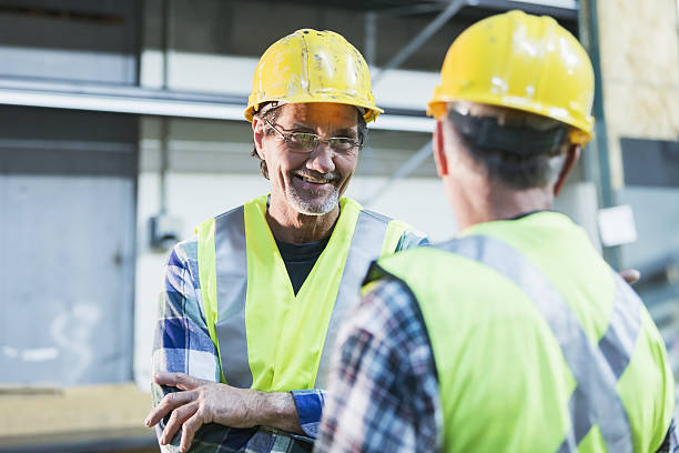 istock Two workers wearing safety vests and hard hats talking 638482076