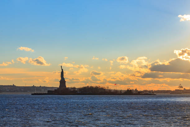 Statue of liberty with orange and yellow cloudscape.