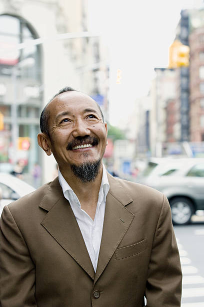 istock Asian mature man looking upward in downtown city 638490106