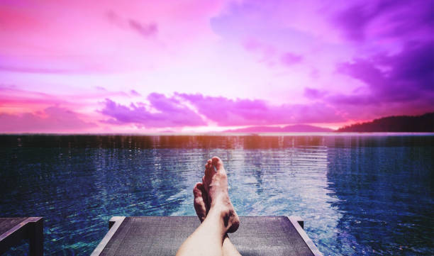 Relaxing in summer holidays, a guy relax on sun bathing bed at swimming pool in sunset