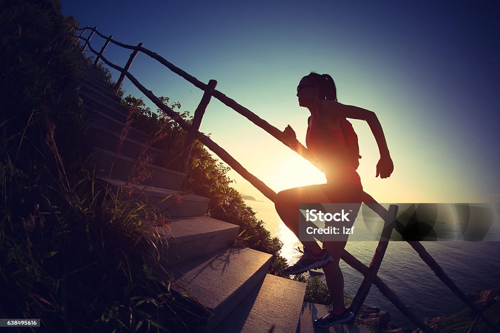 young fitness woman trail runner running up on mountain stairs Dedication Stock Photo