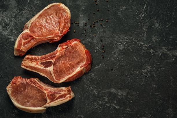 istock Three raw pork steaks on a dark black cement background 638497834