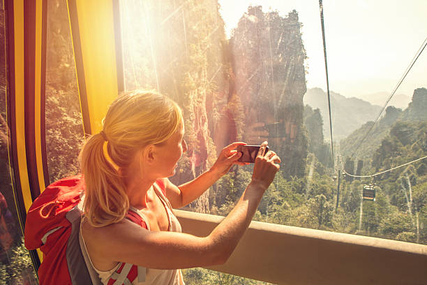 istock Young woman in overhead cable car taking smart phone picture 638499042