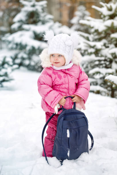Pretty little girl in winter park. She holds her mother's backpack. Outdoor Activities. Close-up portrait