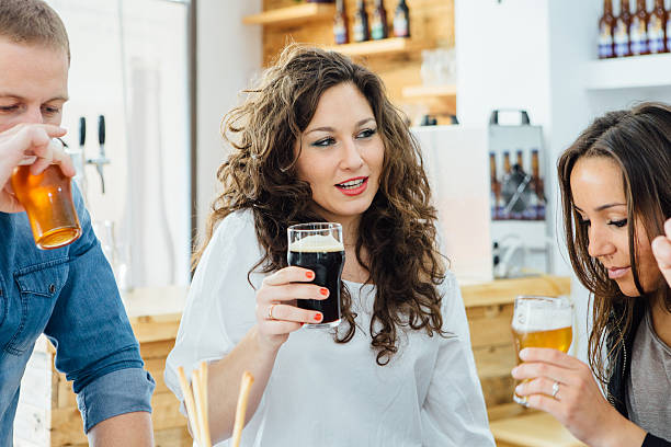 Beautiful woman with curly hair tasting dark craft beer