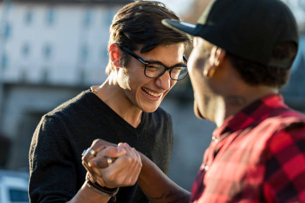good friends joking about their secret handshake hand tight of a couple of good friends on the street at the twilight mixed racial group of friendly children laughing together stock pictures, royalty-free photos & images
