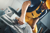 Tile handyman applying adhesive on a tile.