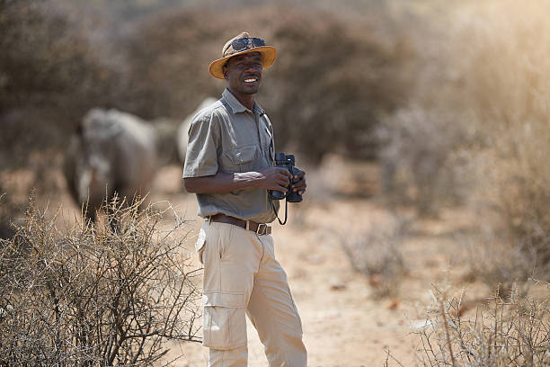 Never a dull moment on the job Portrait of a confident game ranger looking at a group of rhinos in the veld environmentalist stock pictures, royalty-free photos & images
