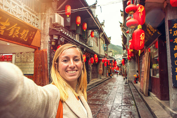 young woman in chinese street taking selfie portrait - single lane road imagens e fotografias de stock