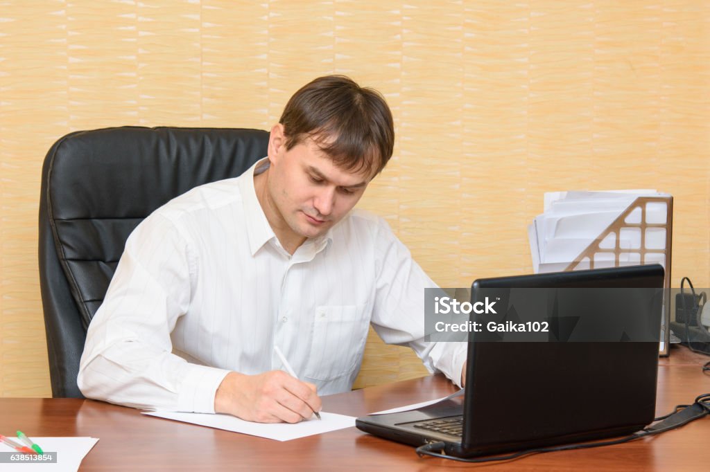 The man at the office of the table writing on paper Adult Stock Photo