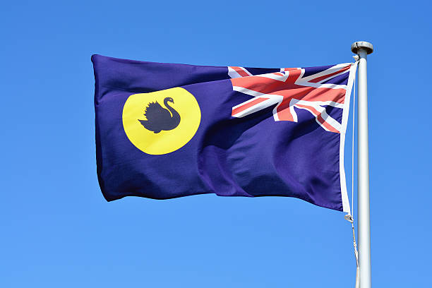 The Western Australia Flag Close-up of Western Australia flag in blue sky background. western australia flag stock pictures, royalty-free photos & images