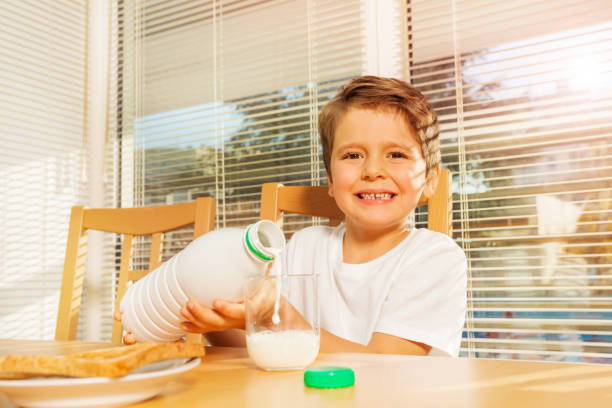 istock Happy boy pouring milk at breakfast in the kitchen 638516734