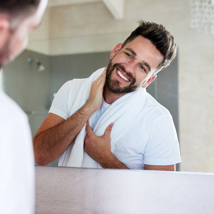 Cropped shot of a handsome young man looking at his face in the bathroom mirror