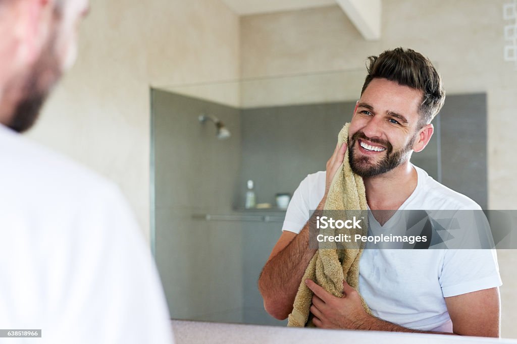 Glowing from the benefits of upholding a good skincare regime Cropped shot of a handsome young man drying off with a towel in the bathroom Men Stock Photo