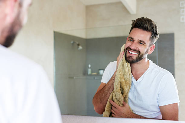 Glowing from the benefits of upholding a good skincare regime Cropped shot of a handsome young man drying off with a towel in the bathroom beard stock pictures, royalty-free photos & images