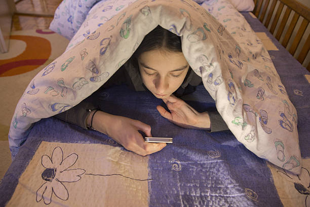 istock Teen Looking At Mobile Phone While Lying Under Blanket 638519022