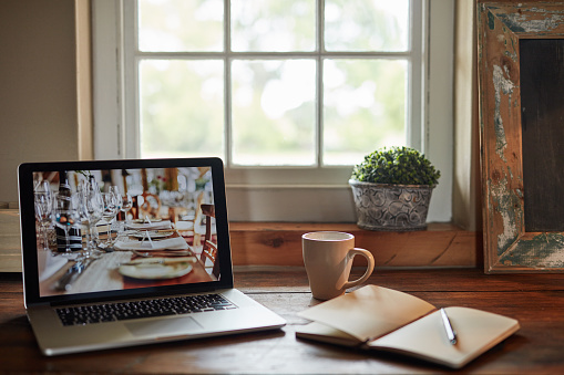 Shot of a table at home with a laptop, notebook and pen