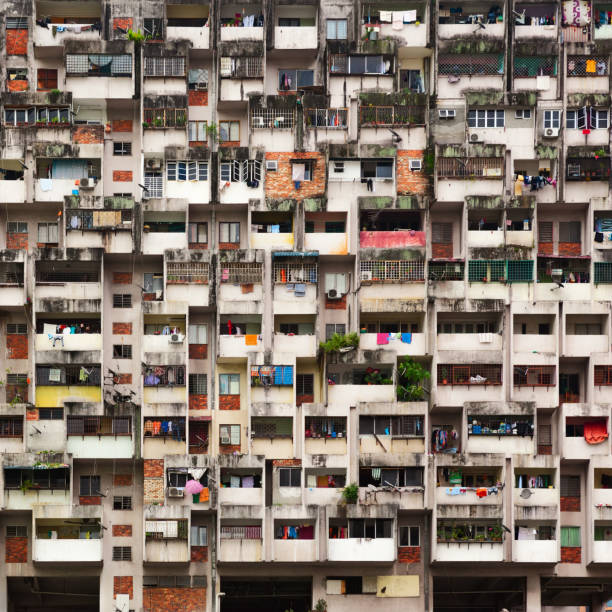 Geometrical pattern of multistory apartment house with group of windows and tenant lumber on balconies. Asian cities street background. Cheap accommodation, social problems in overcrowded countries.