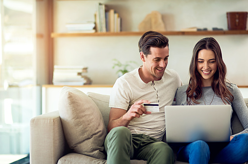 Shot of a happy young couple making a credit card payment on a laptop together at home
