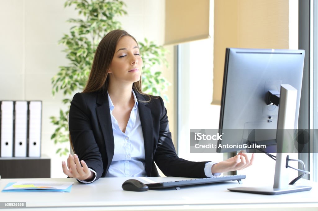 Businesswoman relaxing doing yoga at office Carefree businesswoman relaxing doing yoga exercises at office Business Stock Photo