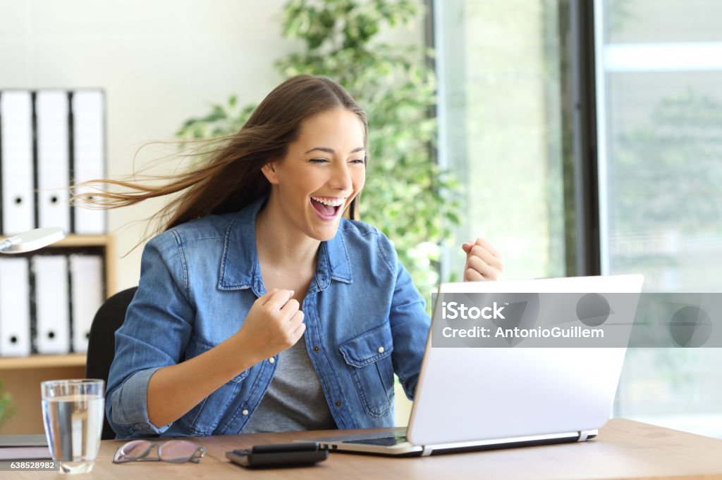 Excited entrepreneur working on line Excited entrepreneur working on line with a laptop at office and the hair moved by the wind Speed Stock Photo