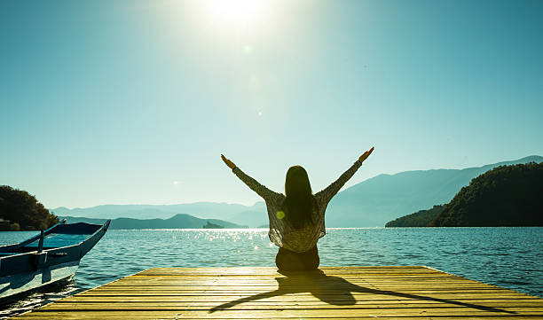 istock Woman sitting on pier with arms outstretched 638529102