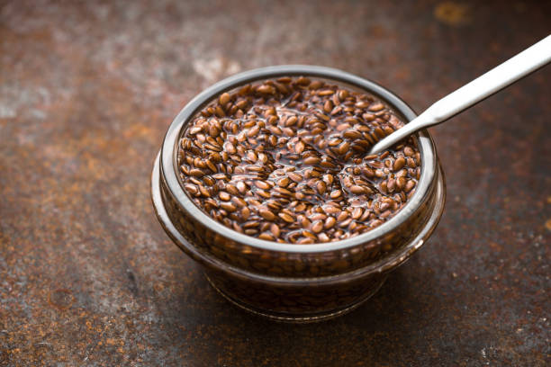 Bowl with flax seeds in water on metal background horizontal Glass bowl with flax seeds in the water on the old metal background horizontal drenched stock pictures, royalty-free photos & images