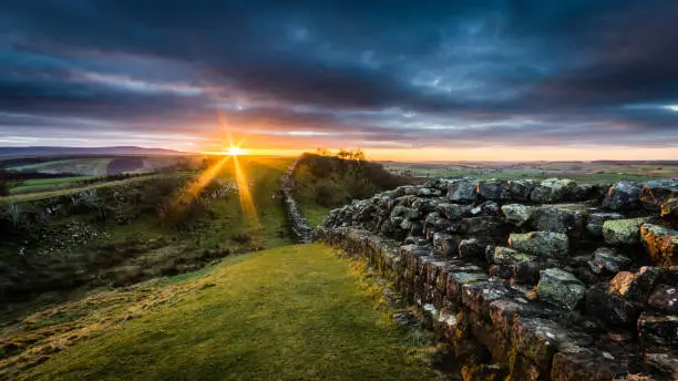 Hadrian's Wall on Walltown Crags at sunset with dramatic clouds.