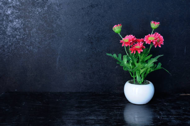 istock Small pot with artificial flowers on black background. 638537426