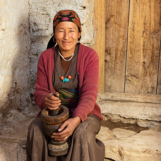 istock Tibetan woman using a mortar to make  flour. Mustang, Nepal 638540416