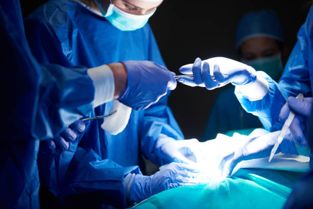 cirujanos que se pasan tijeras entre sí - cirugía fotos fotografías e imágenes de stock