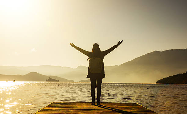 istock Woman standing on pier with arms outstretched 638541266