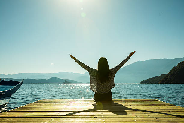 istock Woman sitting on pier with arms outstretched 638543630
