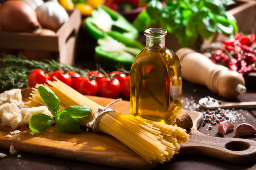 Horizontal shot of a rustic wood table filled with all the ingredients for cooking a traditional italian spaghetti: olive oil, tomatoes, basil, parmesan cheese, garlic, salt, pepper and onion. Soft focus technic used. DSRL studio photo taken with Canon EOS 5D Mk II and Canon EF 70-200mm f/2.8L IS II USM Telephoto Zoom Lens