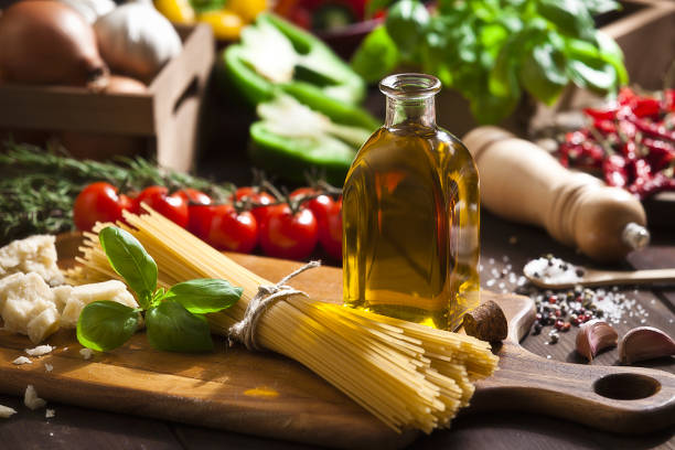 Ingredient for cooking italian spaguetti Horizontal shot of a rustic wood table filled with all the ingredients for cooking a traditional italian spaghetti: olive oil, tomatoes, basil, parmesan cheese, garlic, salt, pepper and onion. Soft focus technic used. DSRL studio photo taken with Canon EOS 5D Mk II and Canon EF 70-200mm f/2.8L IS II USM Telephoto Zoom Lens cooking with garlic stock pictures, royalty-free photos & images