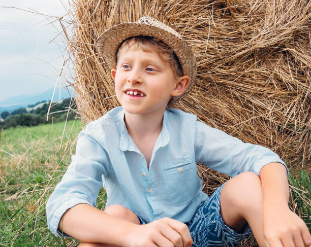 istock Boy sits near big haystack on the field 638549770