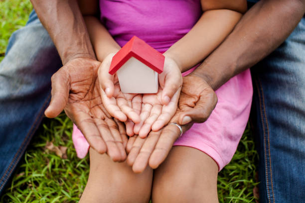 manos de la familia juntos sosteniendo la casa en el parque verde - complejo de viviendas fotografías e imágenes de stock