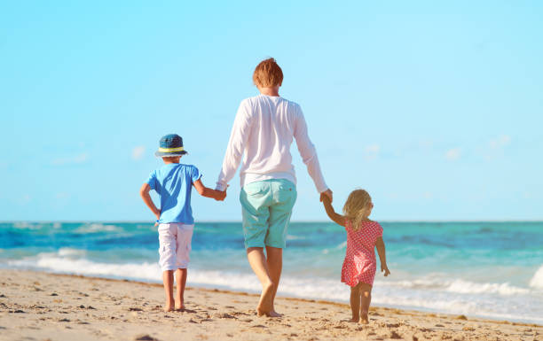istock father and two kids walking on beach 638562194