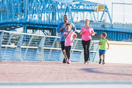 Black family staying fit, power walking on waterfront