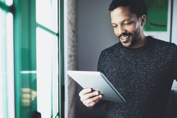 istock Selective focus.Smiling bearded African man reading book on digital 638563122