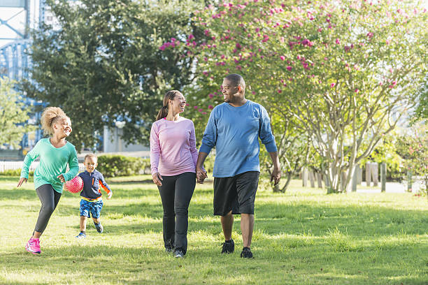 istock Black parents walking in park, children running, playing 638563618