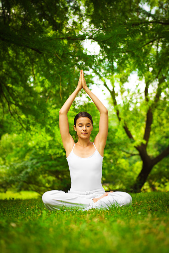 Portrait of young serene woman doing meditation outdoors.
