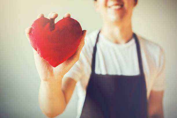 Servicing man in apron holding open armed heart with hands