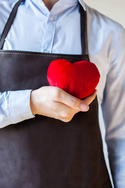 istock Servicing man in apron holding open armed heart with hands 638565490