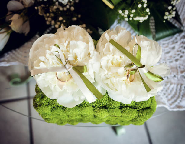 istock White peonies and green flowers with two golden rings. 638565892