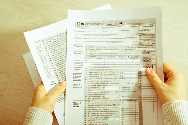 Female hands and tax form A woman sitting at a table and holds a tax form IRS Headquarters Building stock pictures, royalty-free photos & images