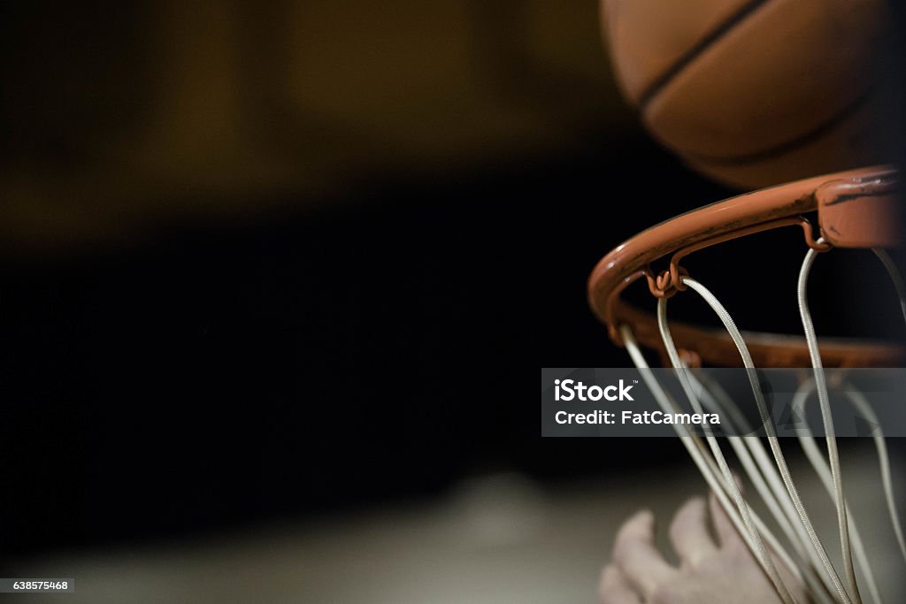 A basketball flying through the air and dropping into basketball hoop Basketball - Sport Stock Photo