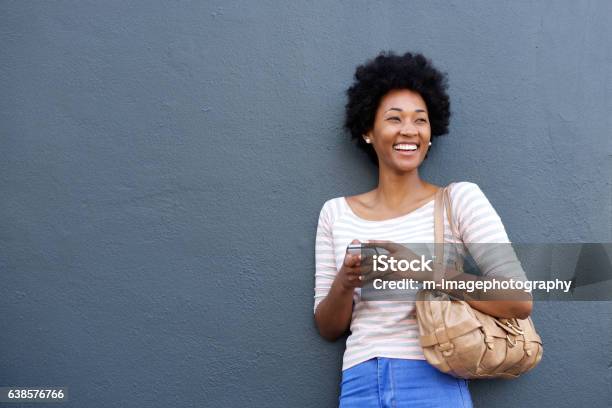 Attractive african woman smiling with mobile phone and bag