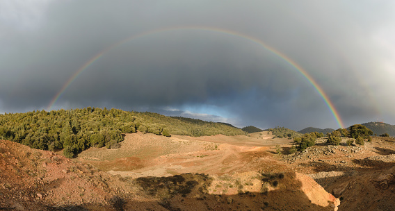Panorama of a rainbow and dark clouds in the Ifrane National Park, Morocco.