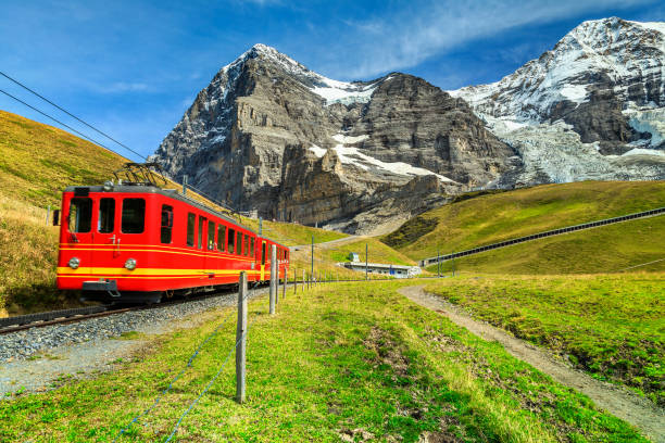 Electric tourist train and Eiger North face, Bernese Oberland, Switzerland Famous electric retro red tourist train coming down from the Jungfraujoch station(top of Europe) in Kleine Scheidegg, Bernese Oberland, Switzerland, Europe jungfrau stock pictures, royalty-free photos & images